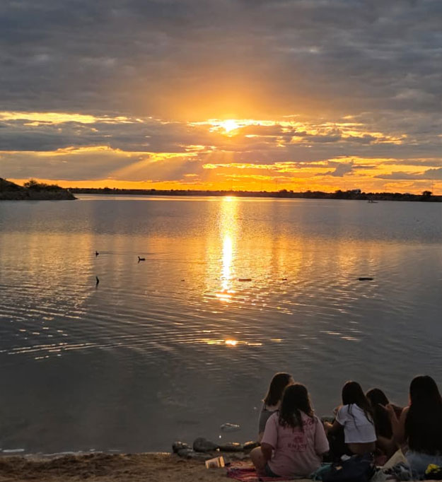 Cielo naranja y violeta reflejado en el agua quieta del Dique Piscu Yaco